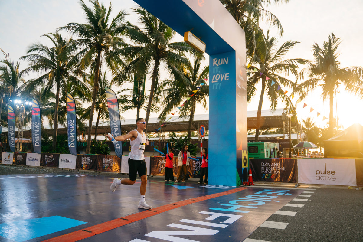 A happy runner crossing the finish line at the Da Nang International Marathon.